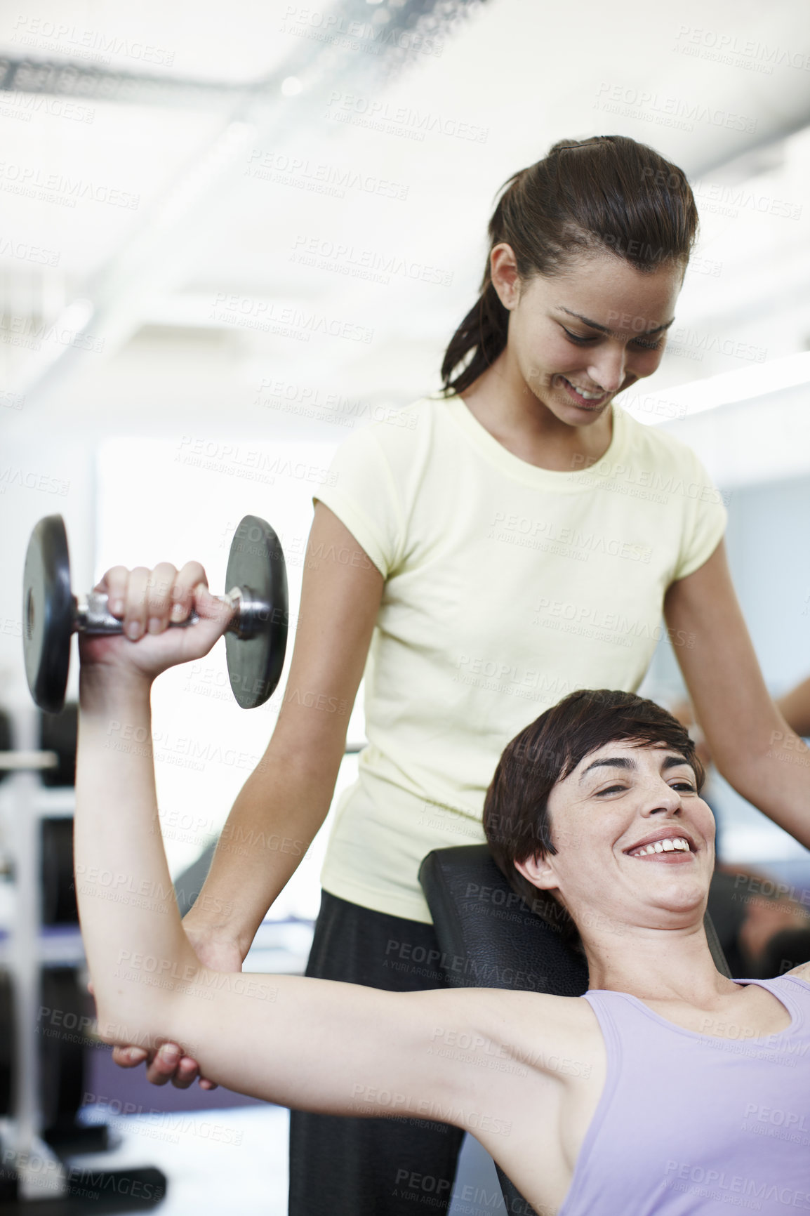 Buy stock photo Cropped shot of an attractive young woman training on the weights with her personal trainer