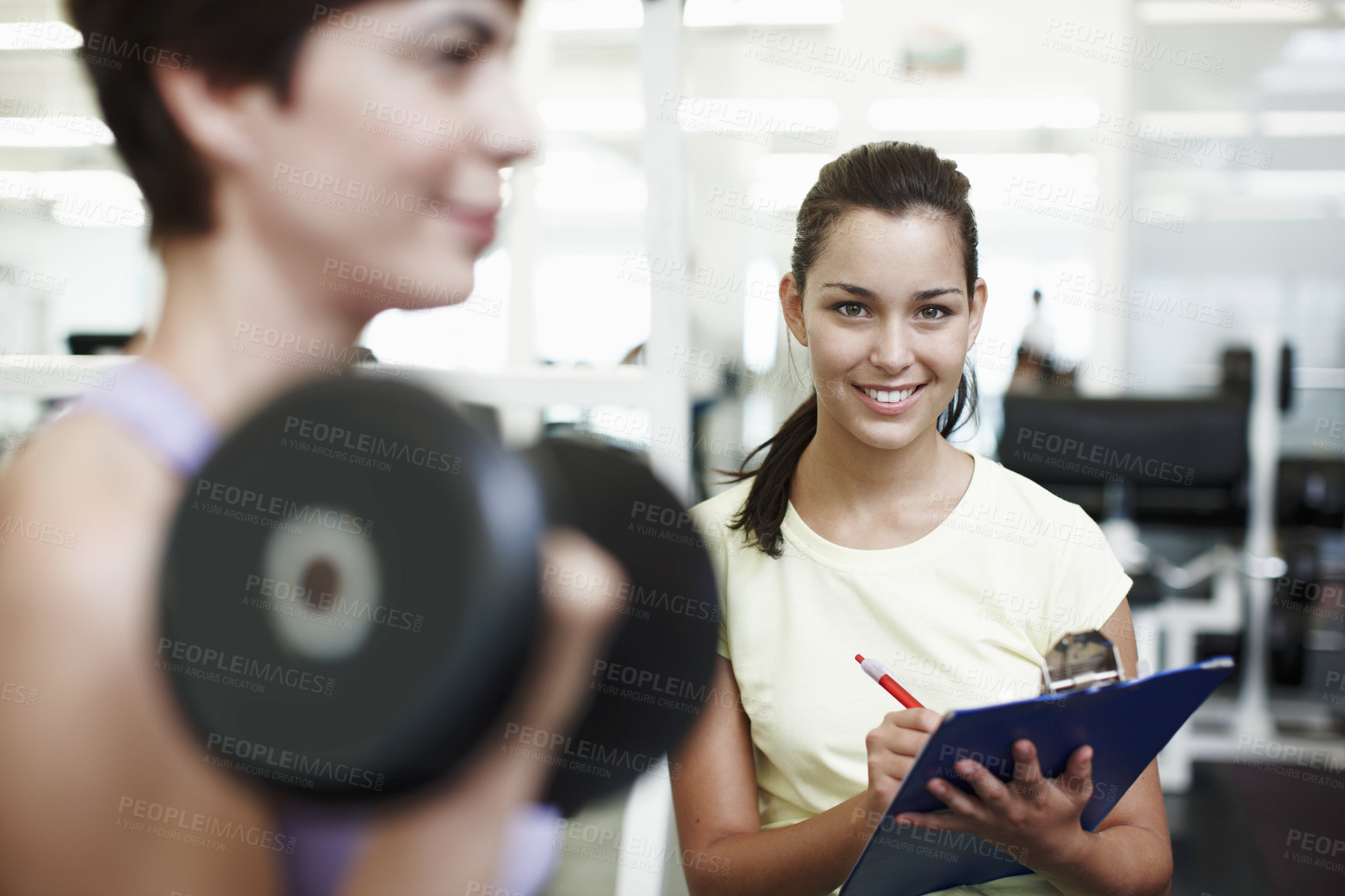 Buy stock photo Coach, woman and clipboard with dumbbell in portrait at gym, notes and test for progress at gym. Personal trainer, people and writing on checklist with stats, fitness and exercise at club in Spain