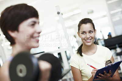 Buy stock photo Cropped shot of an attractive young woman training on the weights with her personal trainer