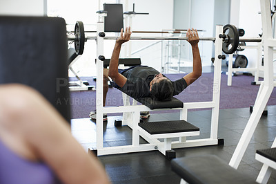 Buy stock photo Cropped shot of a young man working out on the bench press in the gym