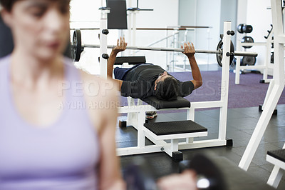 Buy stock photo Cropped shot of a young man working out on the bench press in the gym
