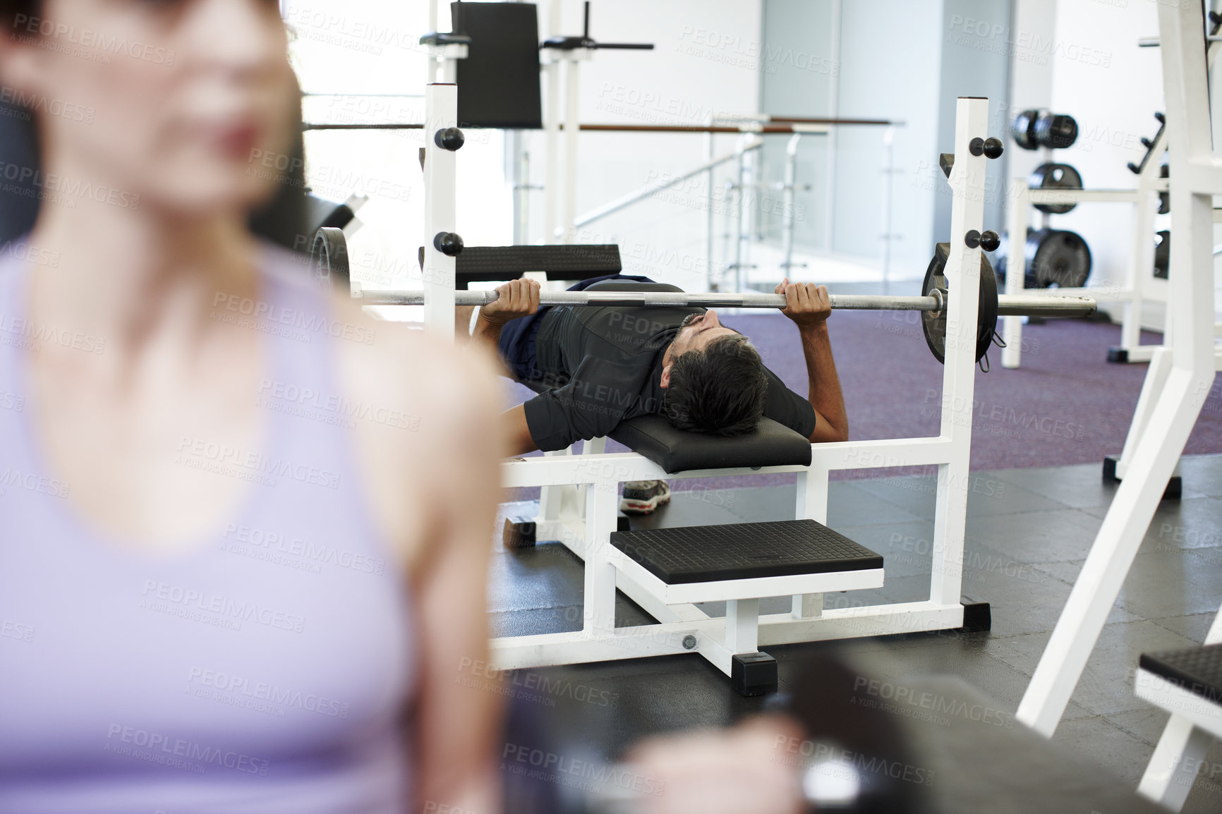 Buy stock photo Cropped shot of a young man working out on the bench press in the gym