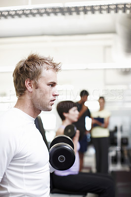 Buy stock photo Cropped shot of a handsome young man working out with weights in the gym