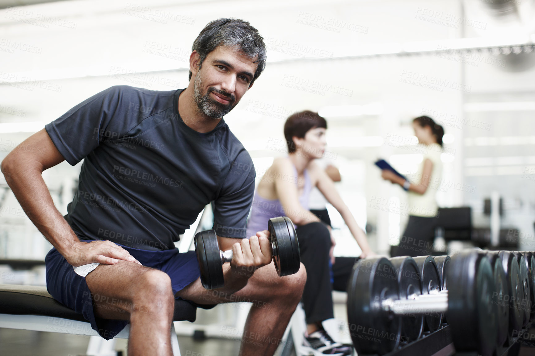 Buy stock photo Cropped portrait of a handsome young man working out with weights in the gym