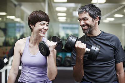 Buy stock photo Cropped shot of two people working out using dumbbells in the gym 