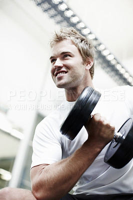 Buy stock photo Cropped shot of a handsome young man working out with a dumbbell in the gym