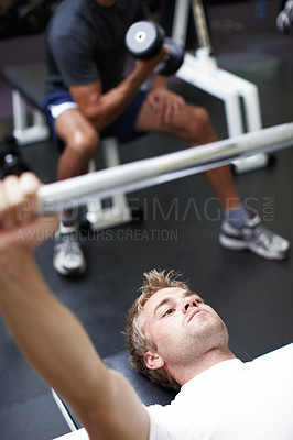 Buy stock photo Cropped shot of two men lifting weights in the gym