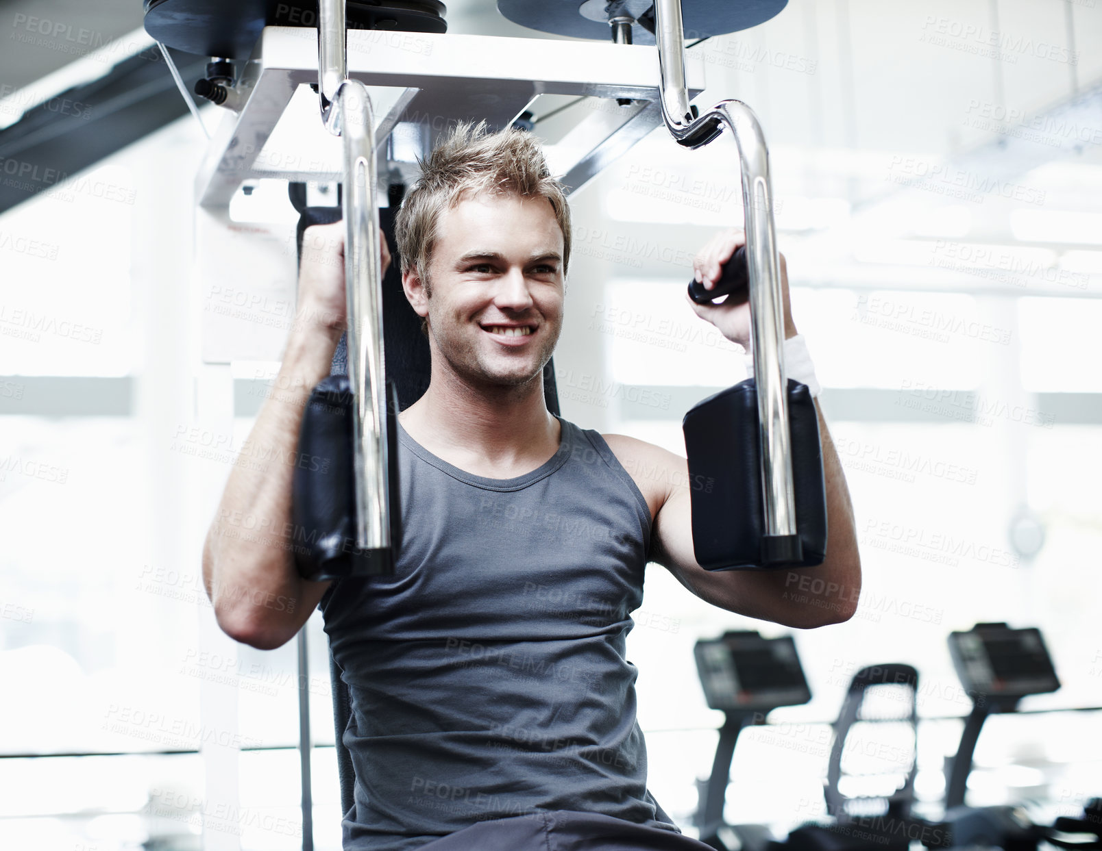 Buy stock photo Cropped shot of a handsome young man using an exercise machine in the gym