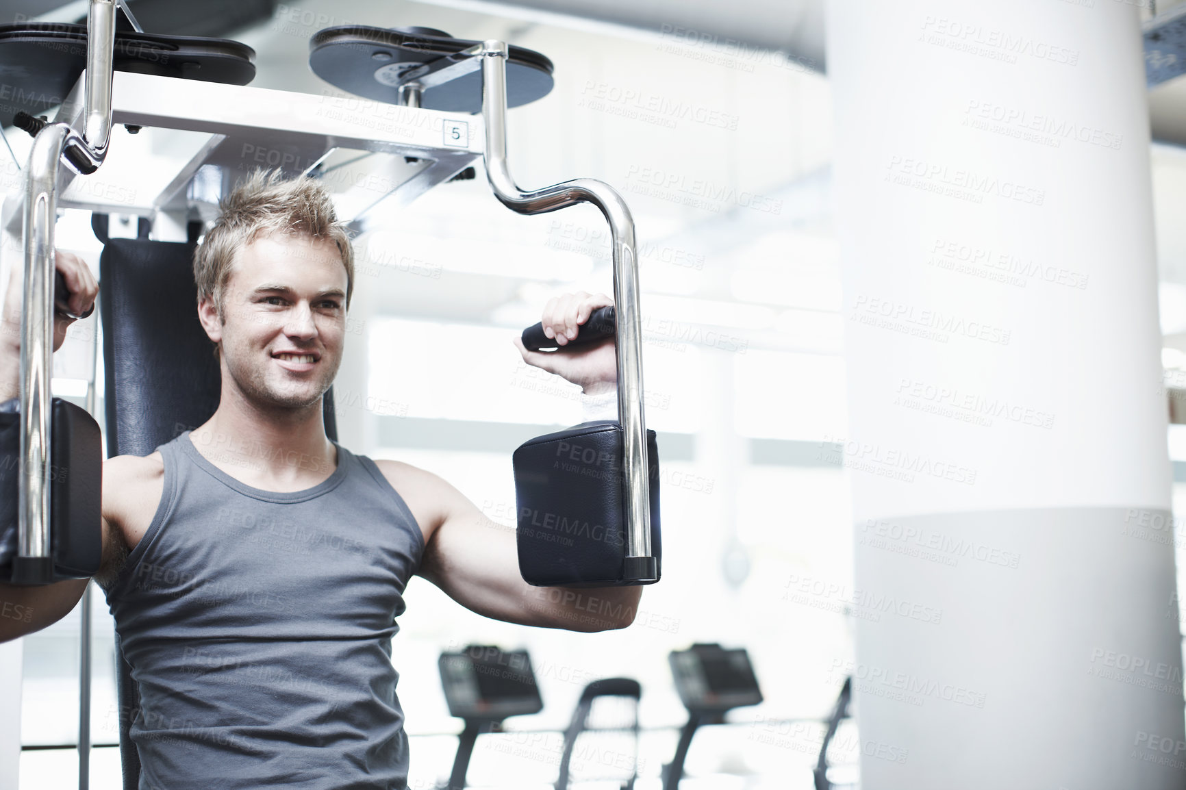 Buy stock photo Cropped shot of a handsome young man using an exercise machine in the gym