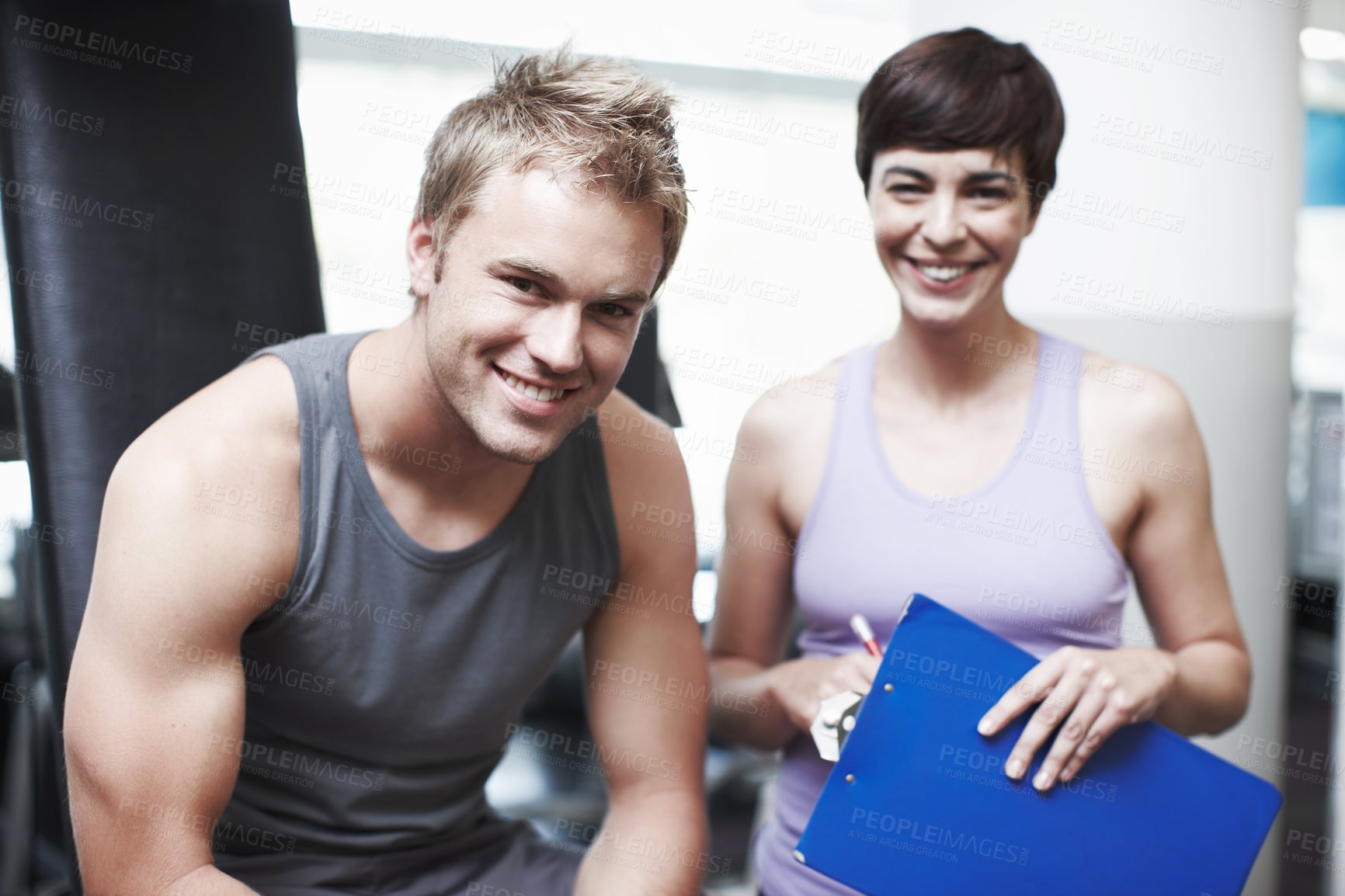 Buy stock photo Cropped portrait of a handsome young man and his personal trainer in the gym