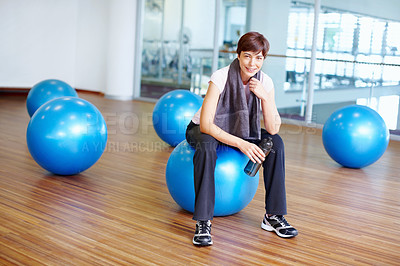 Buy stock photo Portrait of woman sitting on exercise ball with towel and water bottle