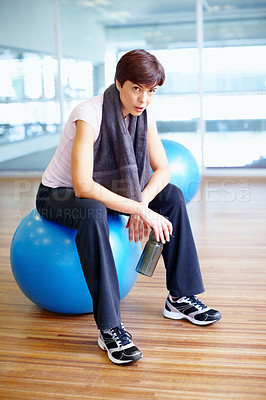 Buy stock photo Full length of woman sitting on exercise ball and taking a breather