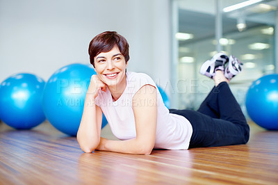 Buy stock photo Full length of smiling woman lying on the gym floor and looking away