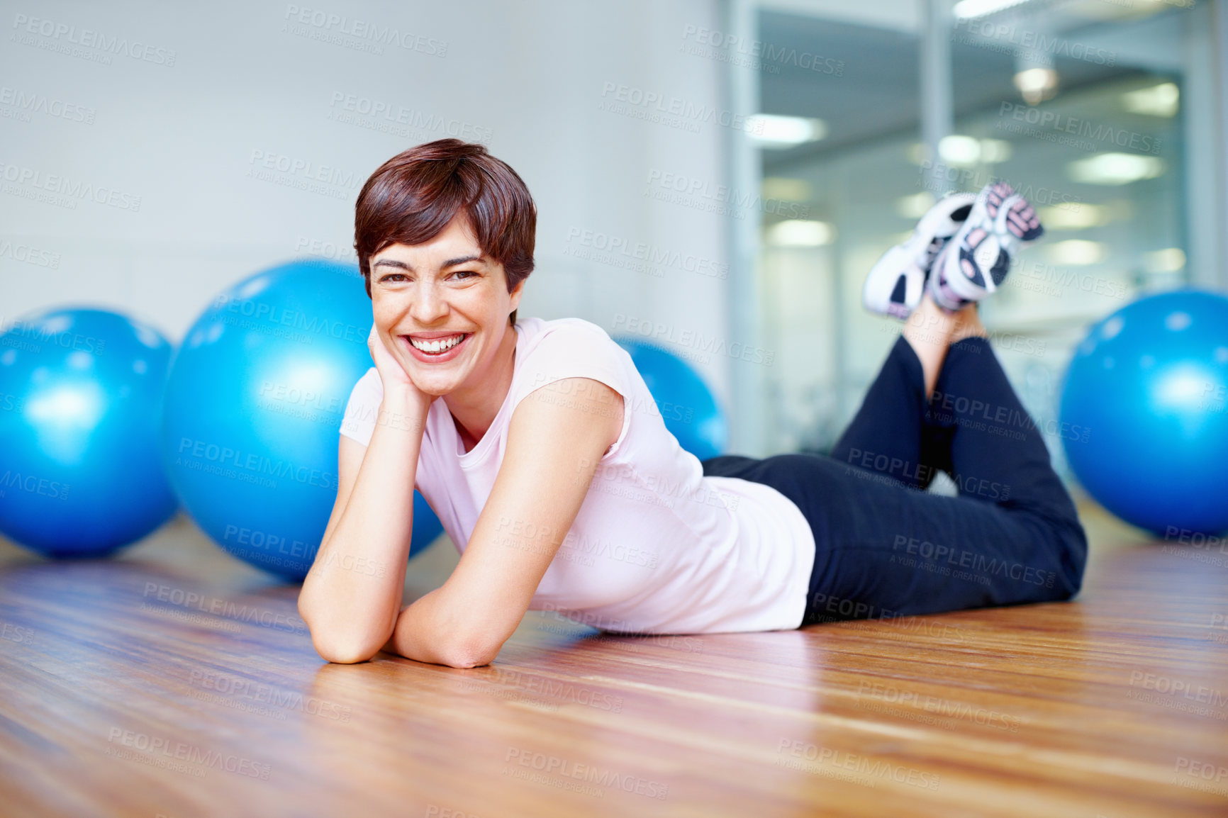 Buy stock photo Portrait of beautiful woman lying on the gym floor and smiling
