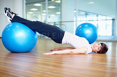 Buy stock photo Portrait of woman lying on the floor and exercising using pilates ball