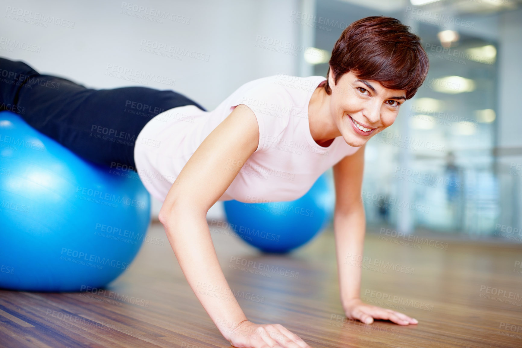 Buy stock photo Portrait of woman doing push ups on pilates ball and smiling