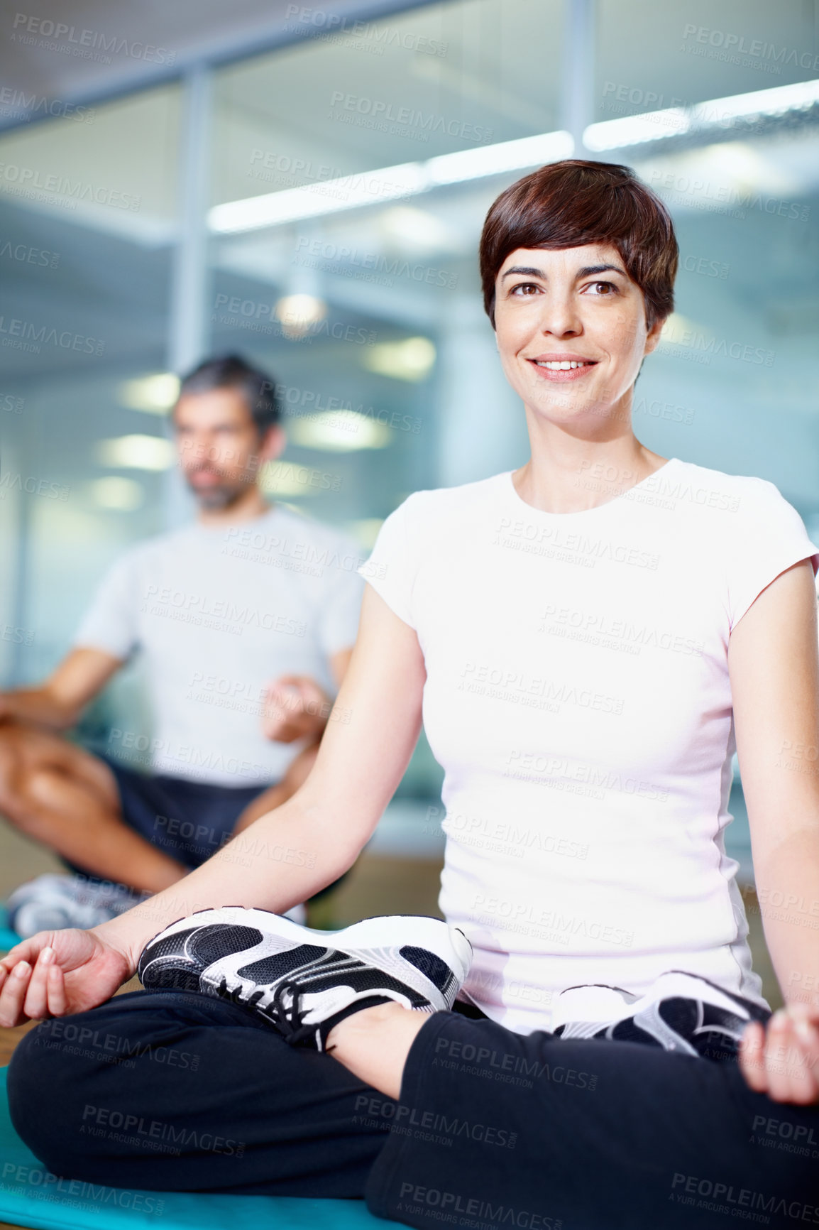 Buy stock photo Full length of a beautiful woman in lotus position with man in background