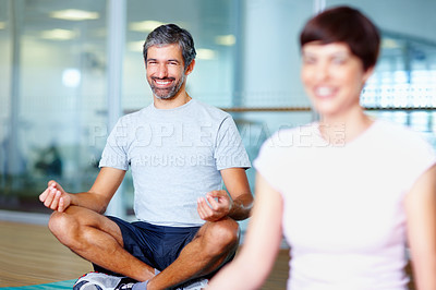 Buy stock photo Smiling man meditating in lotus position with woman in foreground