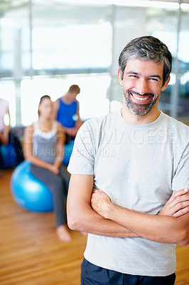Buy stock photo Portrait of smiling male fitness trainer with people practicing yoga in background