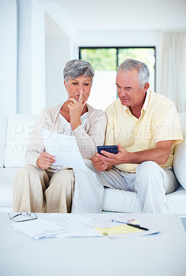 Buy stock photo Mature couple calculating domestic bills while sitting on couch
