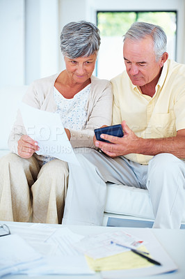 Buy stock photo Happy mature couple calculating domestic bills while sitting on couch