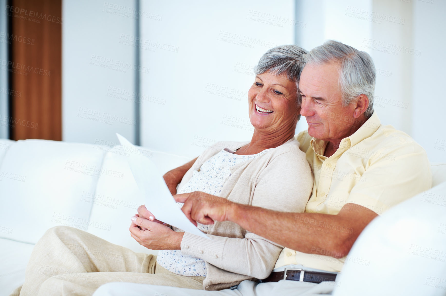 Buy stock photo Smiling mature couple calculating bills while sitting on couch