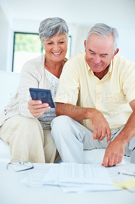 Buy stock photo Smiling mature couple calculating domestic budget while sitting on couch