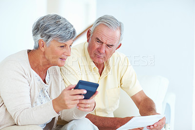 Buy stock photo Mature Caucasian couple calculating domestic budget while sitting on couch
