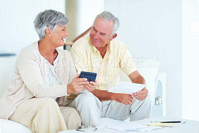 Buy stock photo Cheerful mature couple calculating domestic budget while sitting on couch