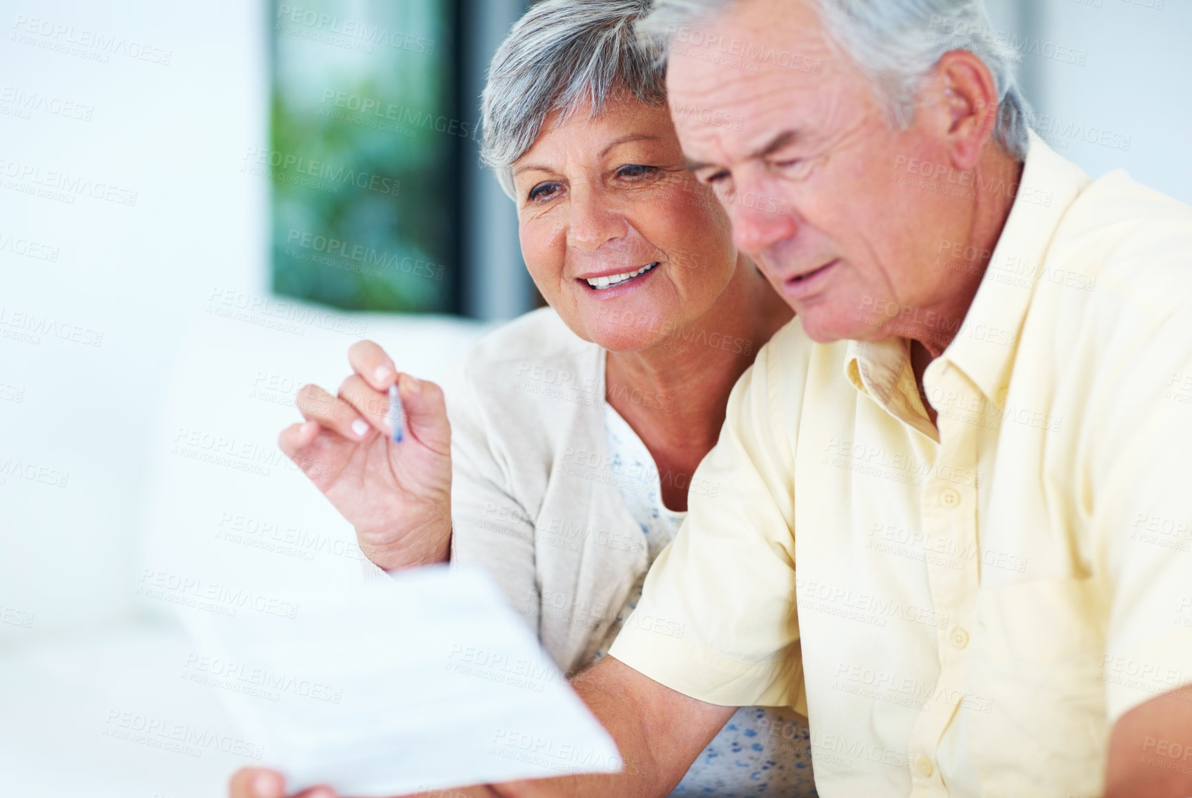 Buy stock photo Happy, mature couple and reading with bills for finance, expenses or budget planning on sofa at home. Elderly, man and woman with smile for pension fund, mortgage or financial payments at house