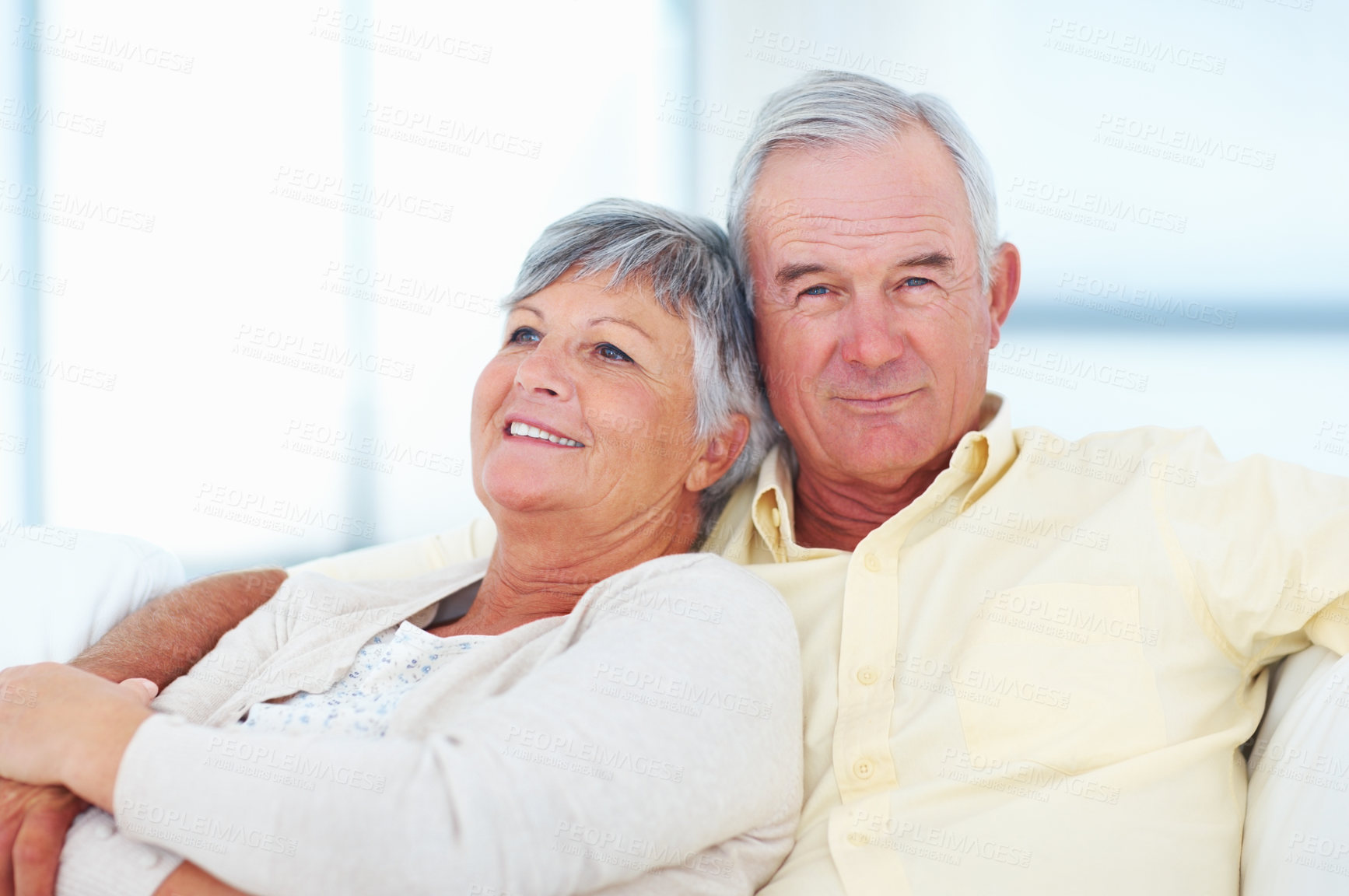 Buy stock photo Old couple, portrait and hug in home, security and love in marriage connection on couch. Elderly people, embrace and commitment to relationship in retirement, bonding and support for comfort on sofa 