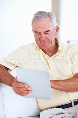 Buy stock photo Good looking mature man using tablet PC while sitting on couch