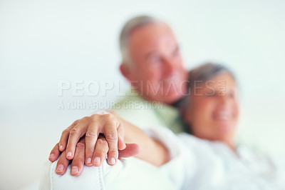 Buy stock photo Senior couple, sofa and holding hands for love, relax and bonding in house with blur, care and support. Man, woman and romance on living room couch for relationship, marriage or commitment with trust