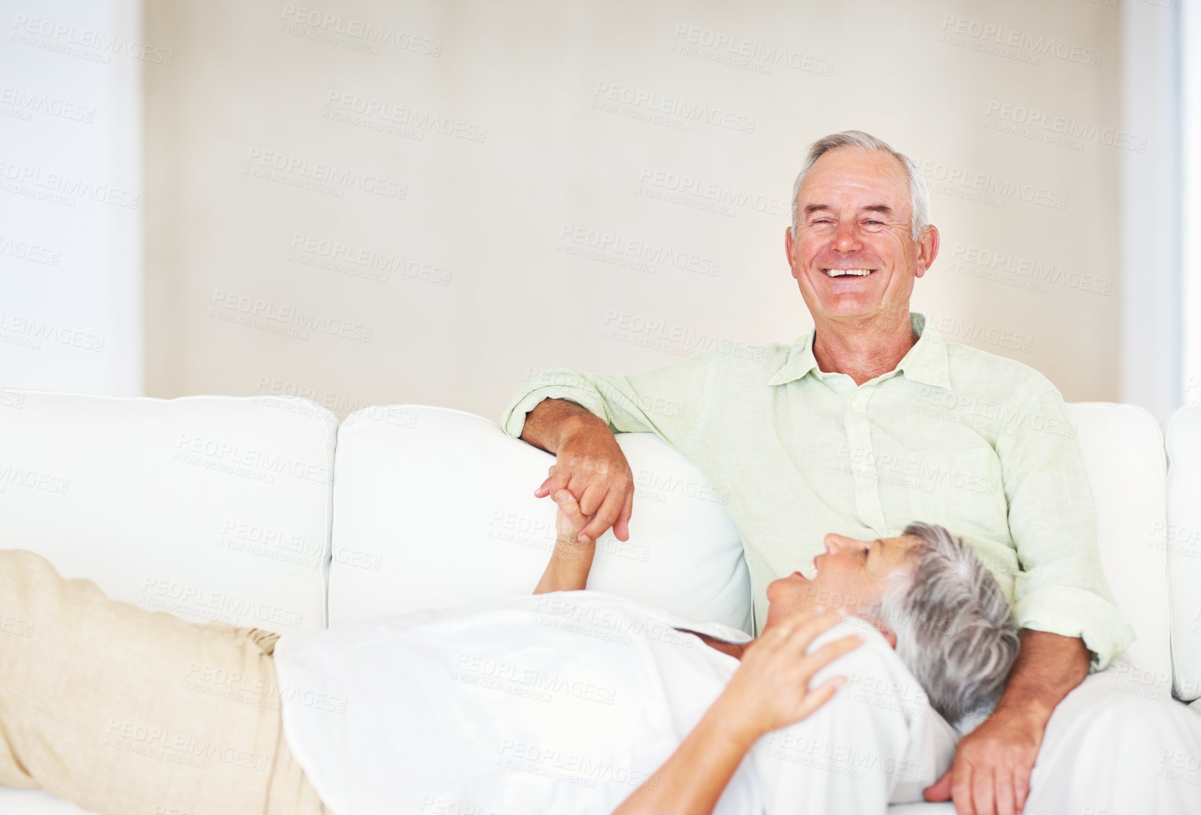 Buy stock photo Senior couple, smile and lying on sofa for relax, bonding and love with support, care and together in home. Elderly people, happy and comfort on couch for weekend break, marriage and holding hands