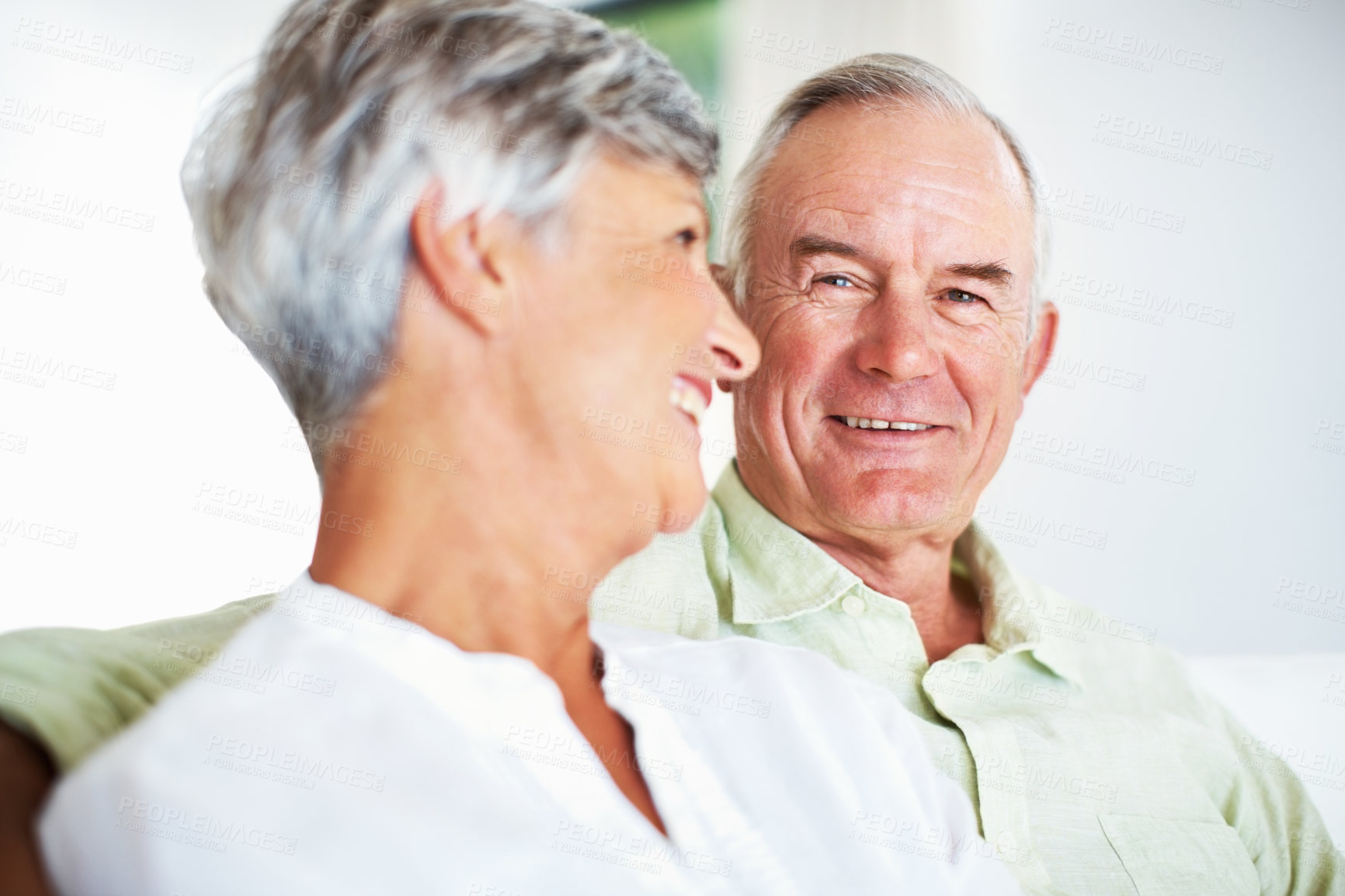 Buy stock photo Senior couple, happy and face on sofa for relax, bonding and love with support, care and together in home. Elderly people, hug and comfort on couch for weekend break, marriage and embrace with trust