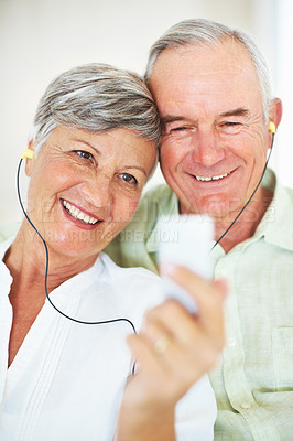 Buy stock photo Home, senior couple and listening with earphones for music, hearing and connection for bonding together. Living room, man and woman in retirement with mp3 player, blues and classic pop for relaxation