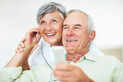 Buy stock photo Smiling mature man and woman listening music while relaxing at home