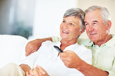 Buy stock photo Happy, mature couple and watching tv with sofa in relax for movie, shows or online streaming at home. Elderly, man and woman with smile for comfort, hug or bonding by television together at house