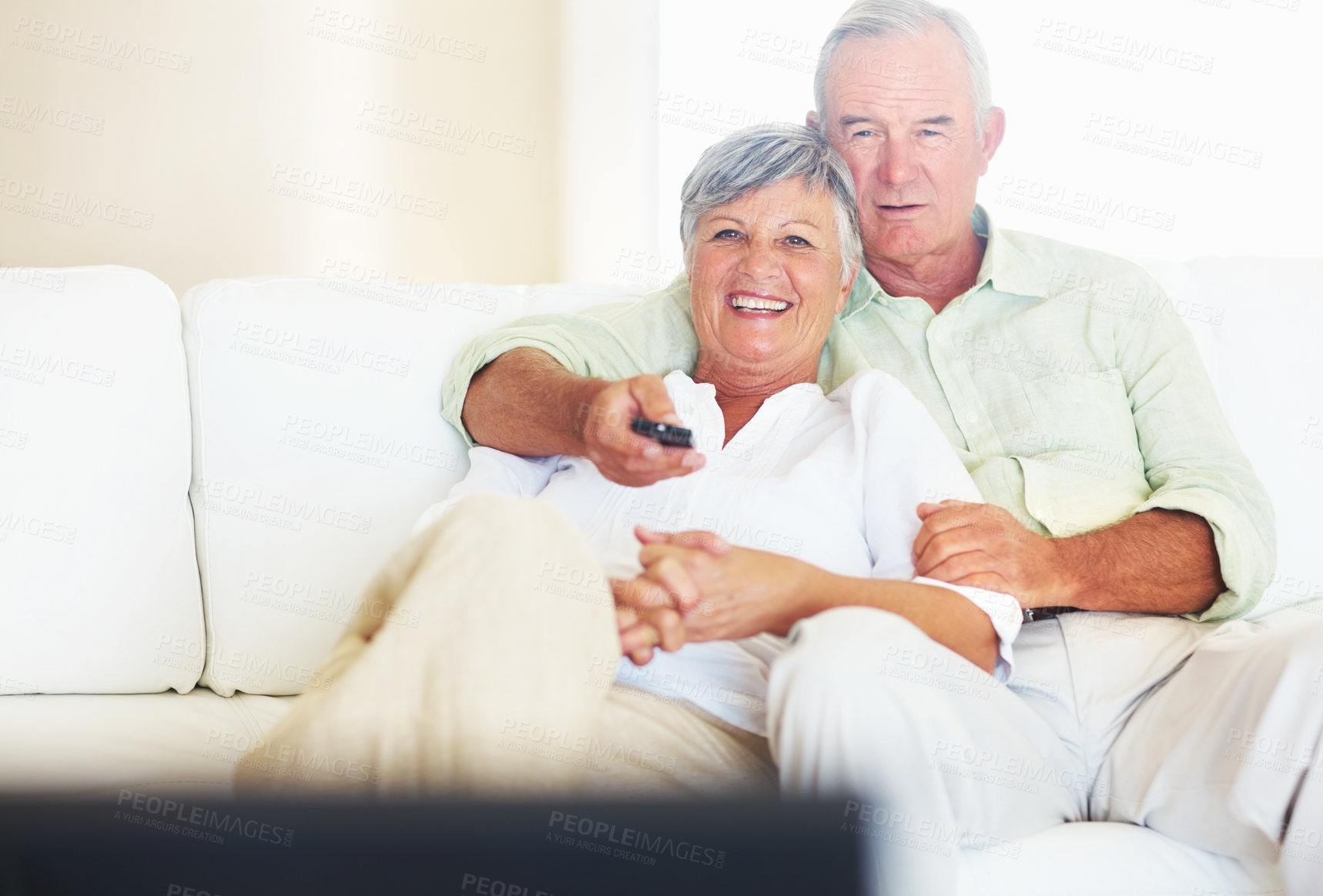 Buy stock photo Mature man changing channels while watching television with smiling woman