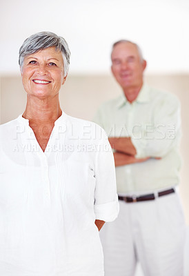 Buy stock photo Portrait of beautiful mature woman smiling with man standing in background