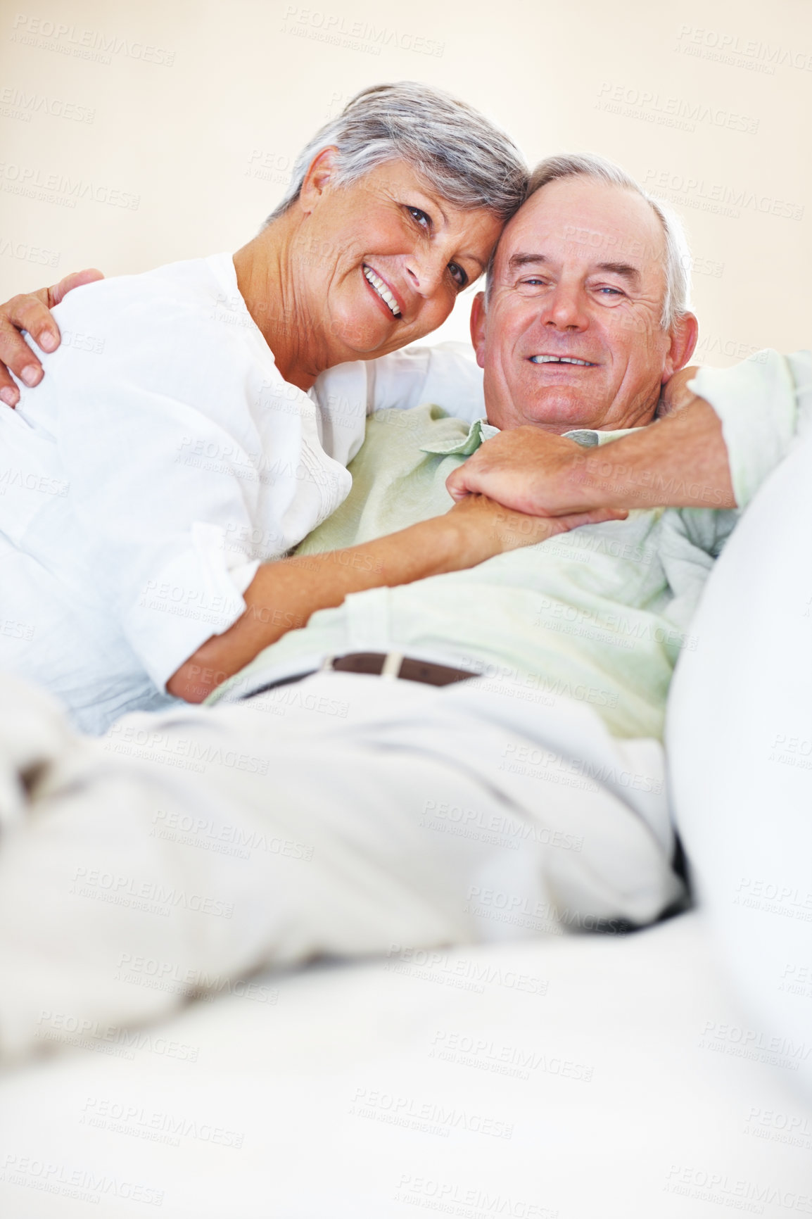 Buy stock photo Elderly couple, hug and portrait in home for bonding, relax and love with support, care and romance. Senior people, smile and connection on sofa for weekend break, marriage and embrace with trust