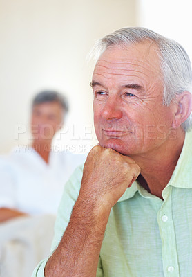 Buy stock photo Thoughtful mature man thinking in living room with woman in background