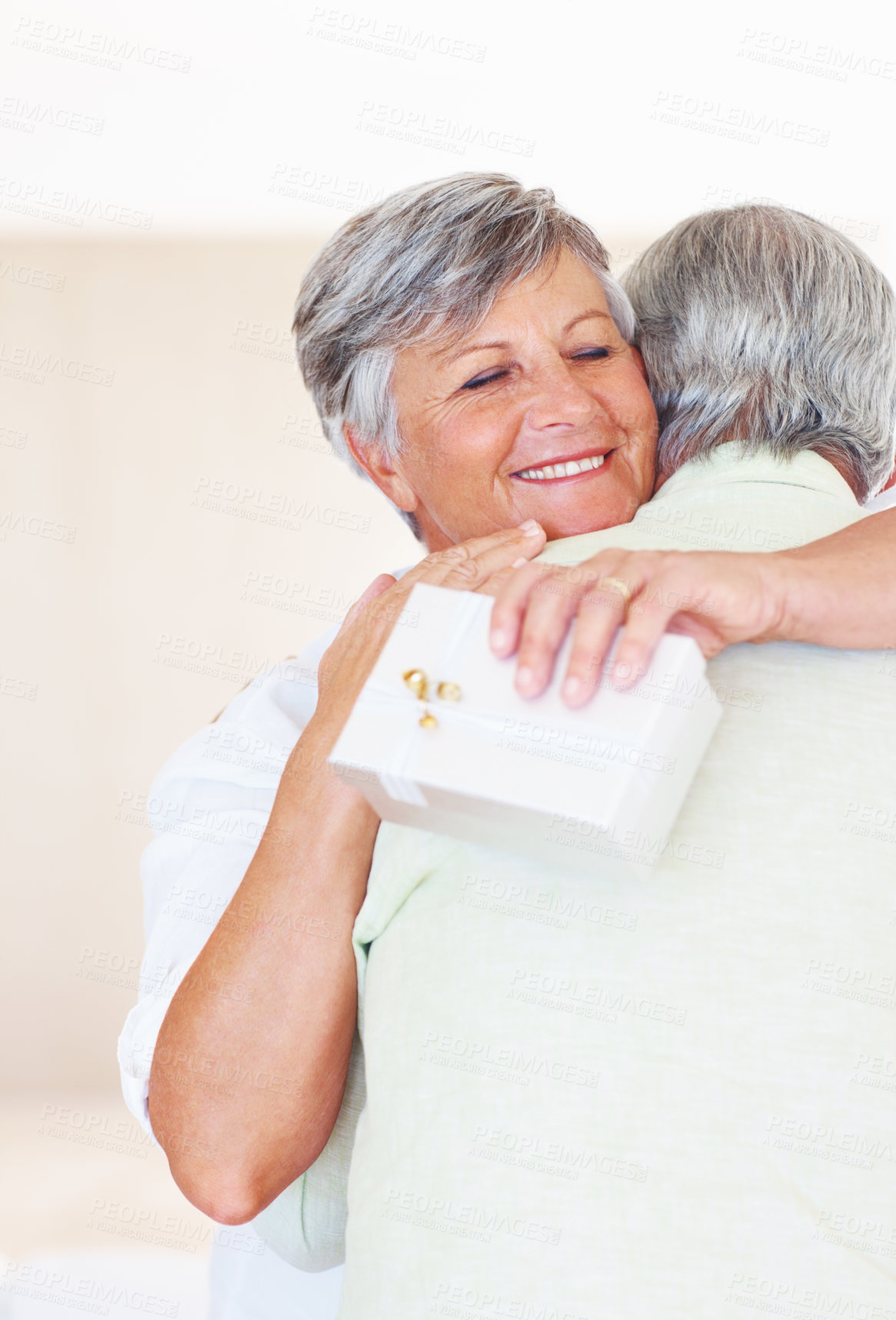 Buy stock photo Happy, mature couple and hug with love for gift, surprise or anniversary together at home. Elderly, man and woman with smile for comfort, bonding or romantic in celebration for birthday at house