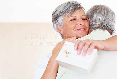 Buy stock photo Closeup of smiling mature woman hugging man after receiving gift