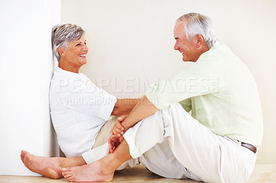 Buy stock photo Senior couple, happy and conversation for love, relax and bonding in house with smile, care and support. Man, woman and romance on lounge floor for relationship, marriage and communication with trust