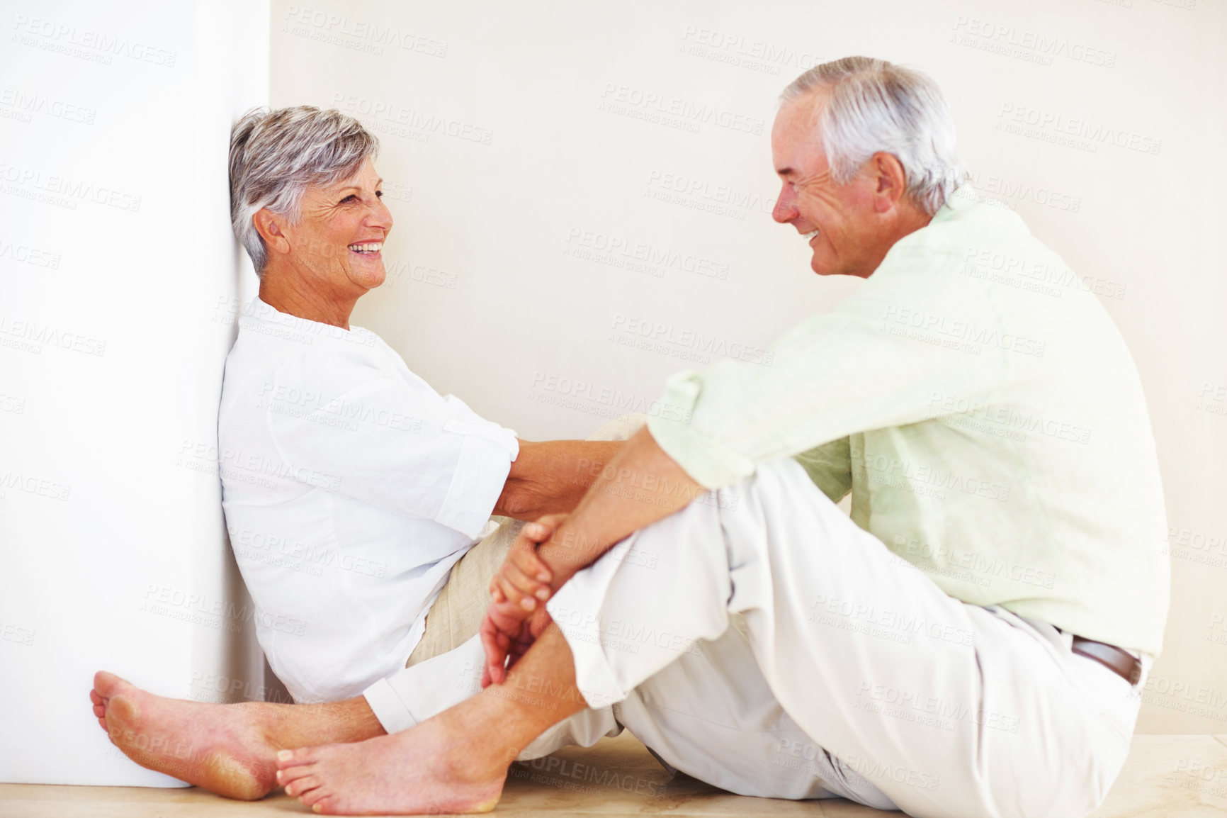 Buy stock photo Senior couple, happy and conversation for love, relax and bonding in house with smile, care and support. Man, woman and romance on lounge floor for relationship, marriage and communication with trust