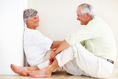 Buy stock photo Elderly couple, happy and conversation for love, relax and bonding in house with smile, care or support. Man, woman and romance on lounge floor for relationship, marriage and communication with trust