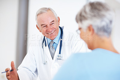 Buy stock photo Cheerful male doctor smiling discussing medical report with mature female