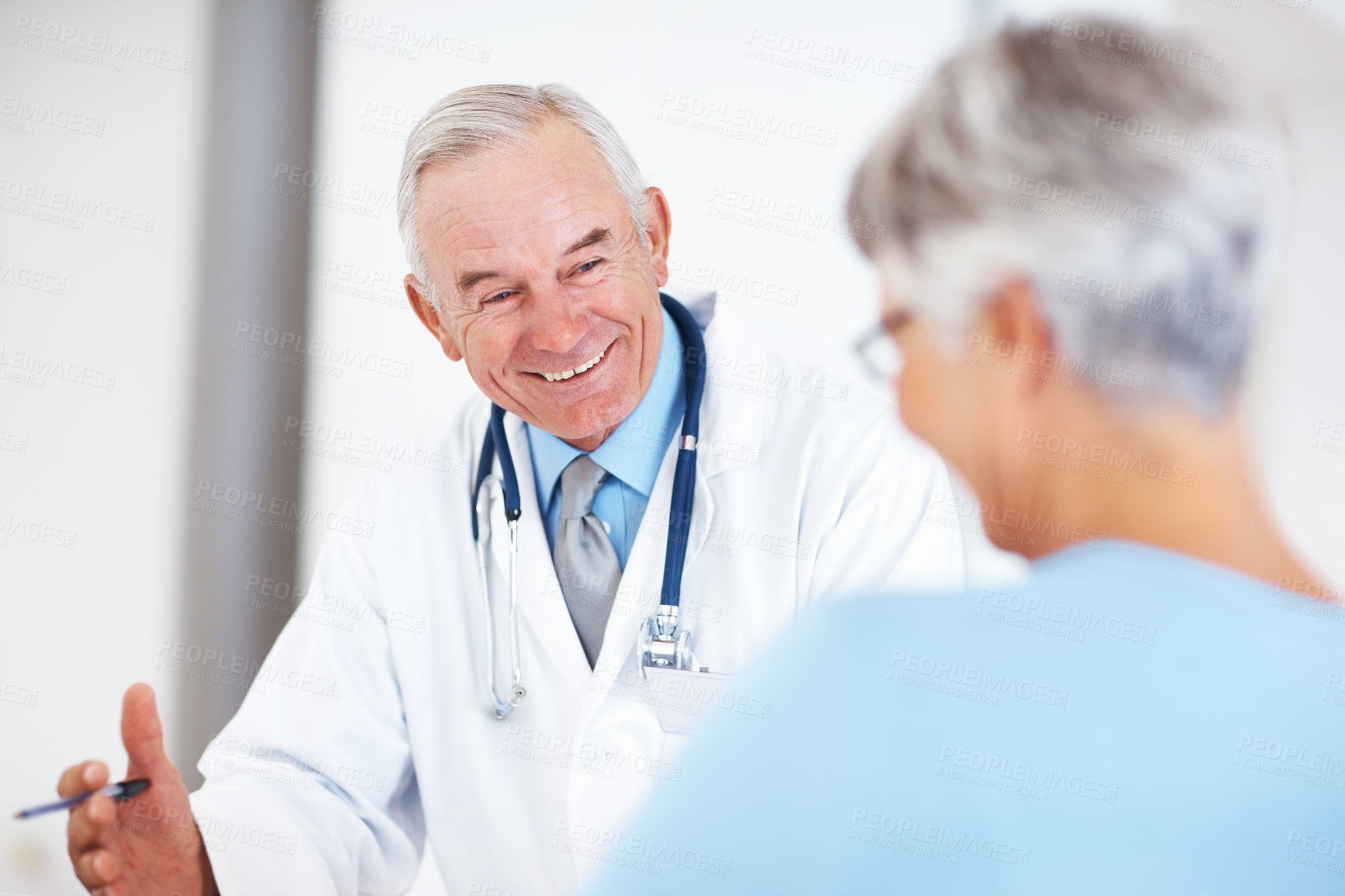 Buy stock photo Cheerful male doctor smiling discussing medical report with mature female
