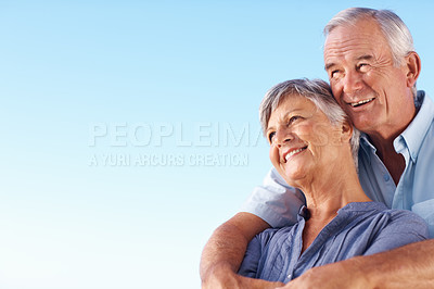 Buy stock photo Smiling mature man embracing beautiful woman against blue sky